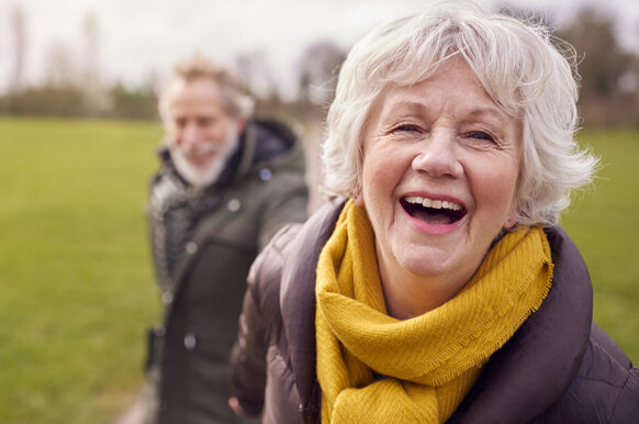 Portrait Of Loving Senior Couple Enjoying Autumn Or Winter Walk Through Park Together