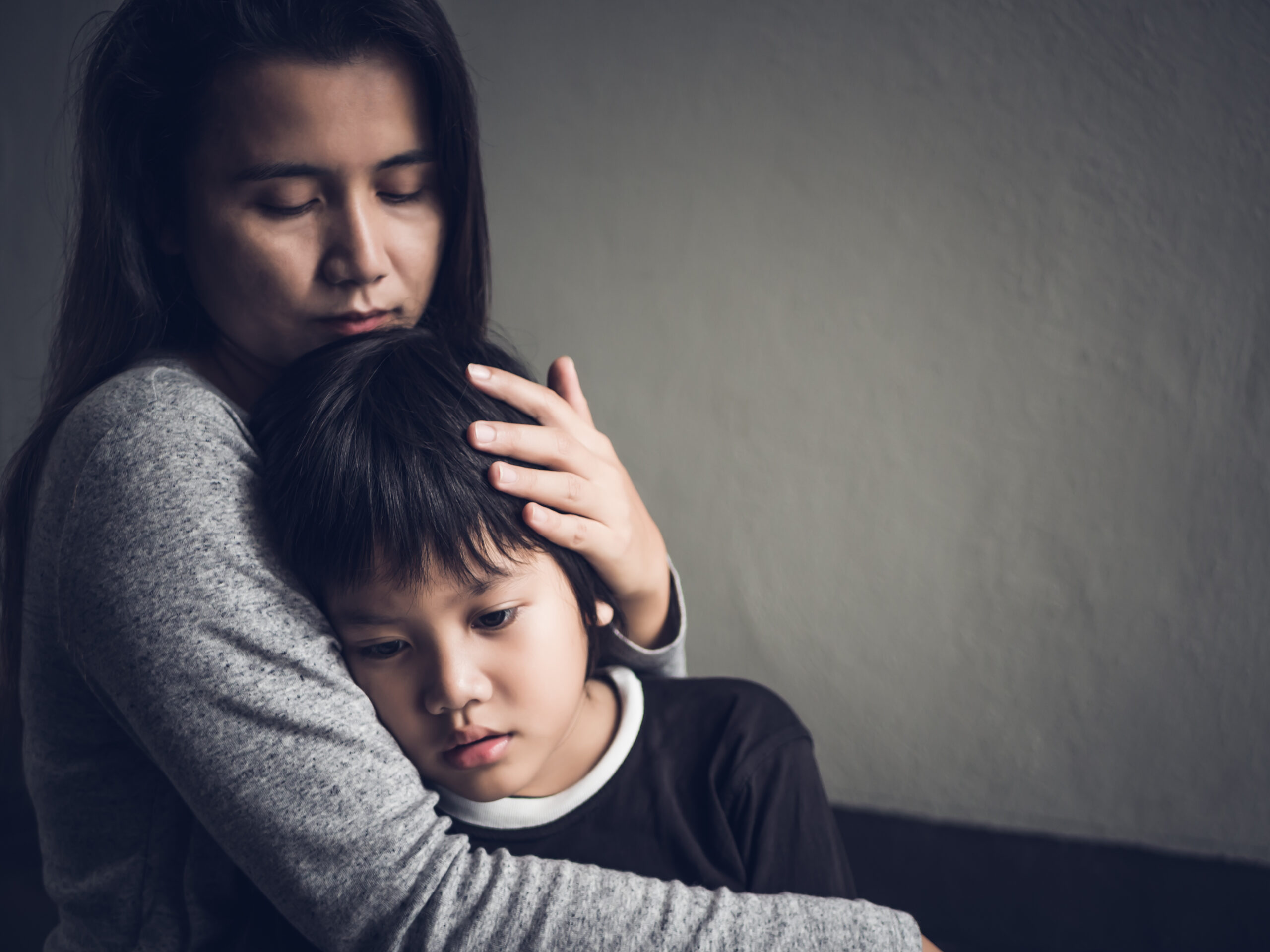 Sad little boy being hugged by his mother at home. Parenthood, Love and togetherness concept.